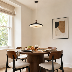 black pleated pendant light above a dining table by a bright window