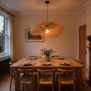 warm bamboo pendant light above a set dining table at dusk