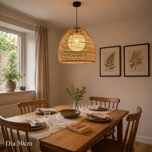 Rattan pendant light with yellow inner sphere above a warm dining table