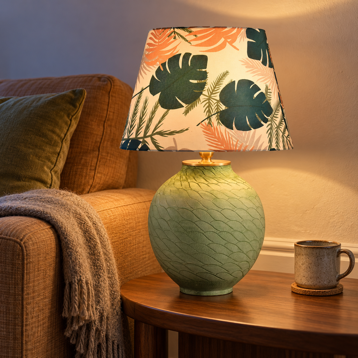 Pale green textured ceramic table lamp with leaf-print shade beside a sofa