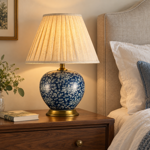 Navy floral table lamp with pleated shade on a bedroom bedside table