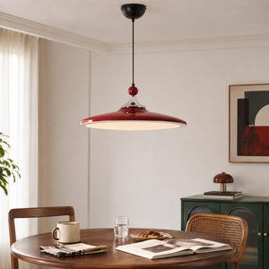 red iron pendant light above a dining table with woven chairs