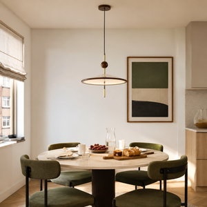 beige iron pendant light above a dining table with green chairs