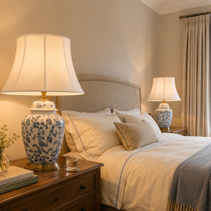 blue floral ceramic table lamp glowing on a bedroom nightstand