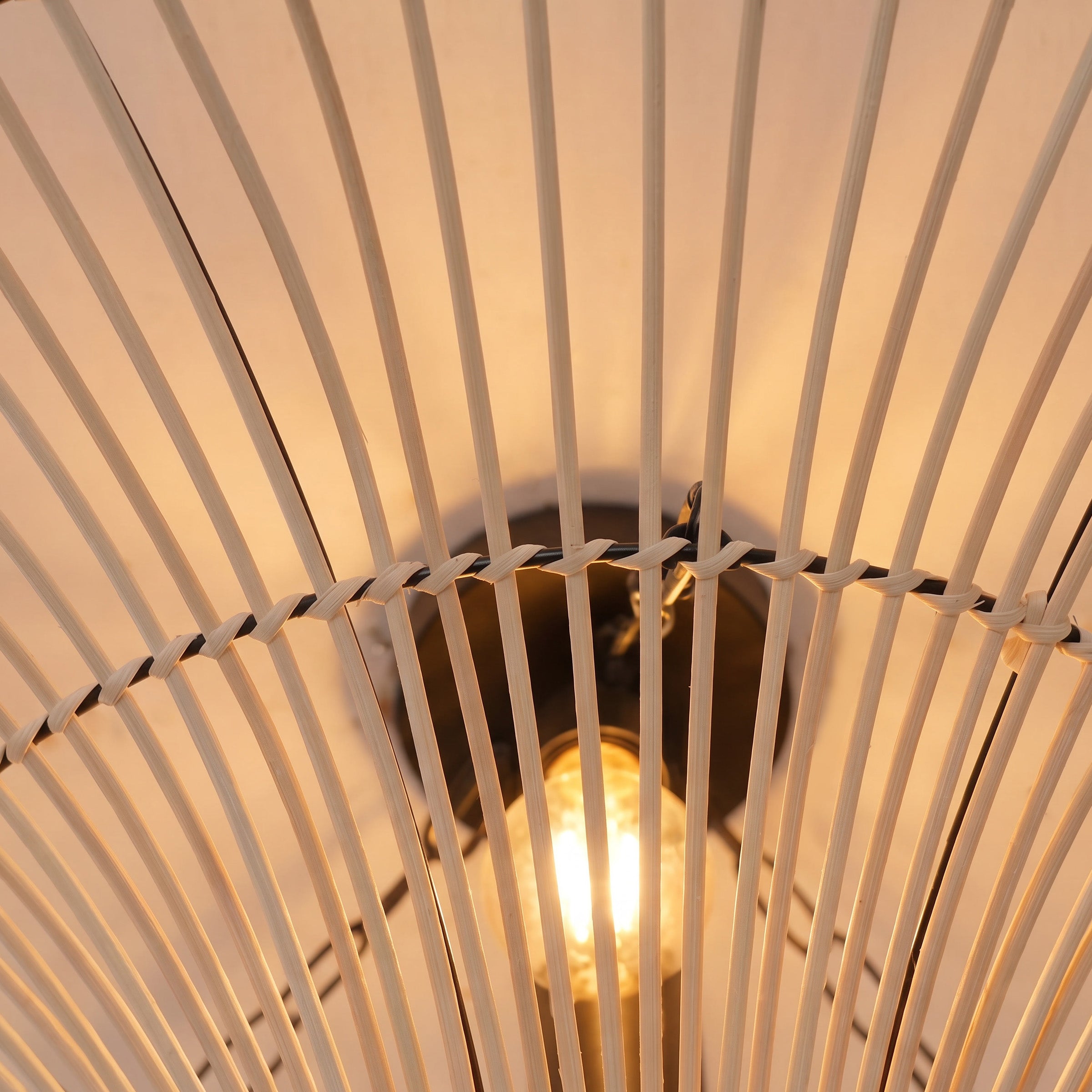 Close-up of warm bulb glowing through the natural rattan saucer shade