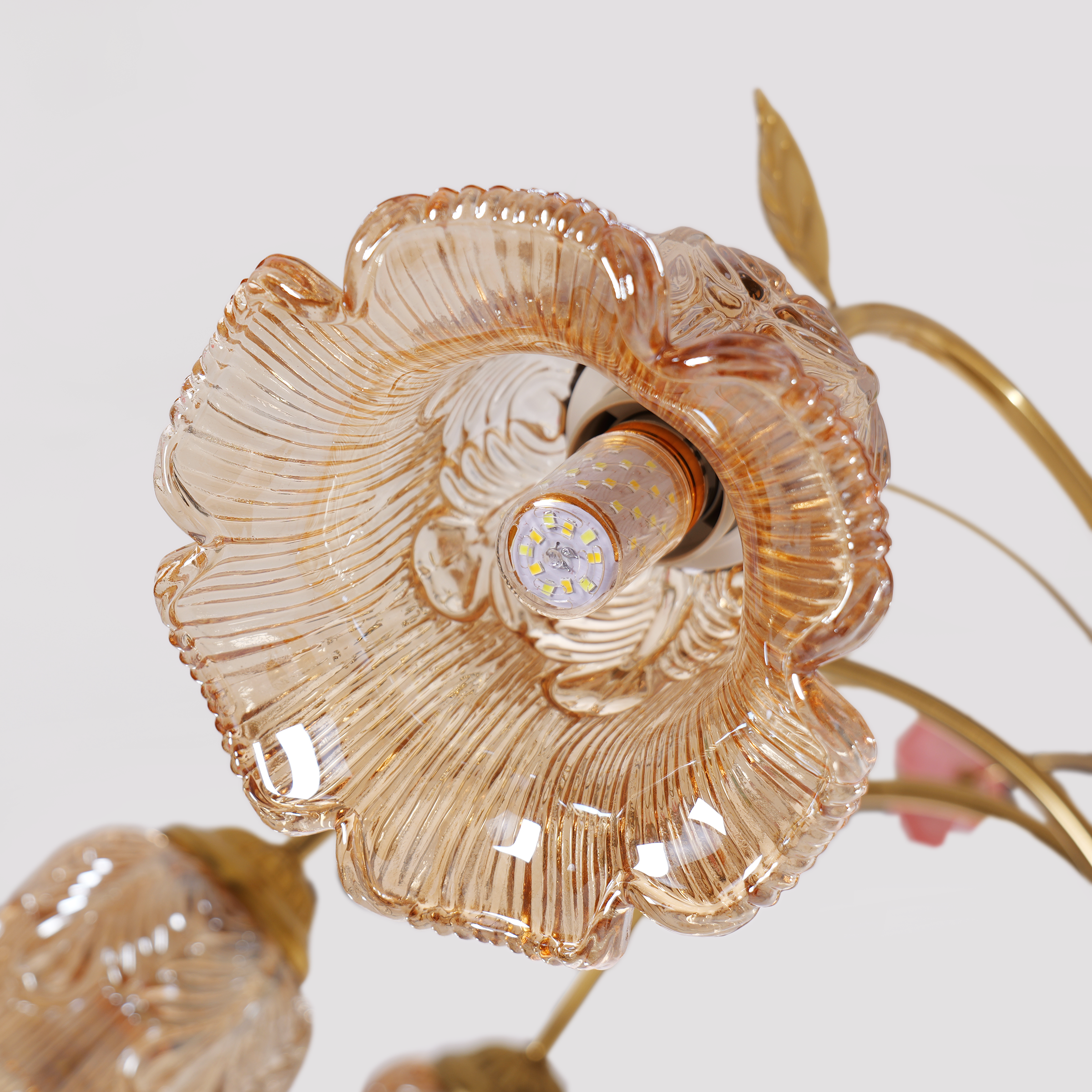 gold 8-light chandelier with pink floral glass shades glowing above a dining table