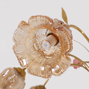 gold 8-light chandelier with pink floral glass shades glowing above a dining table