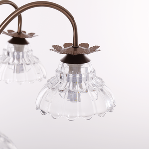 gold 6-light floral glass chandelier adding soft light to a bedroom