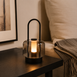 portable lantern-style ambient table lamp glowing on a bedside table