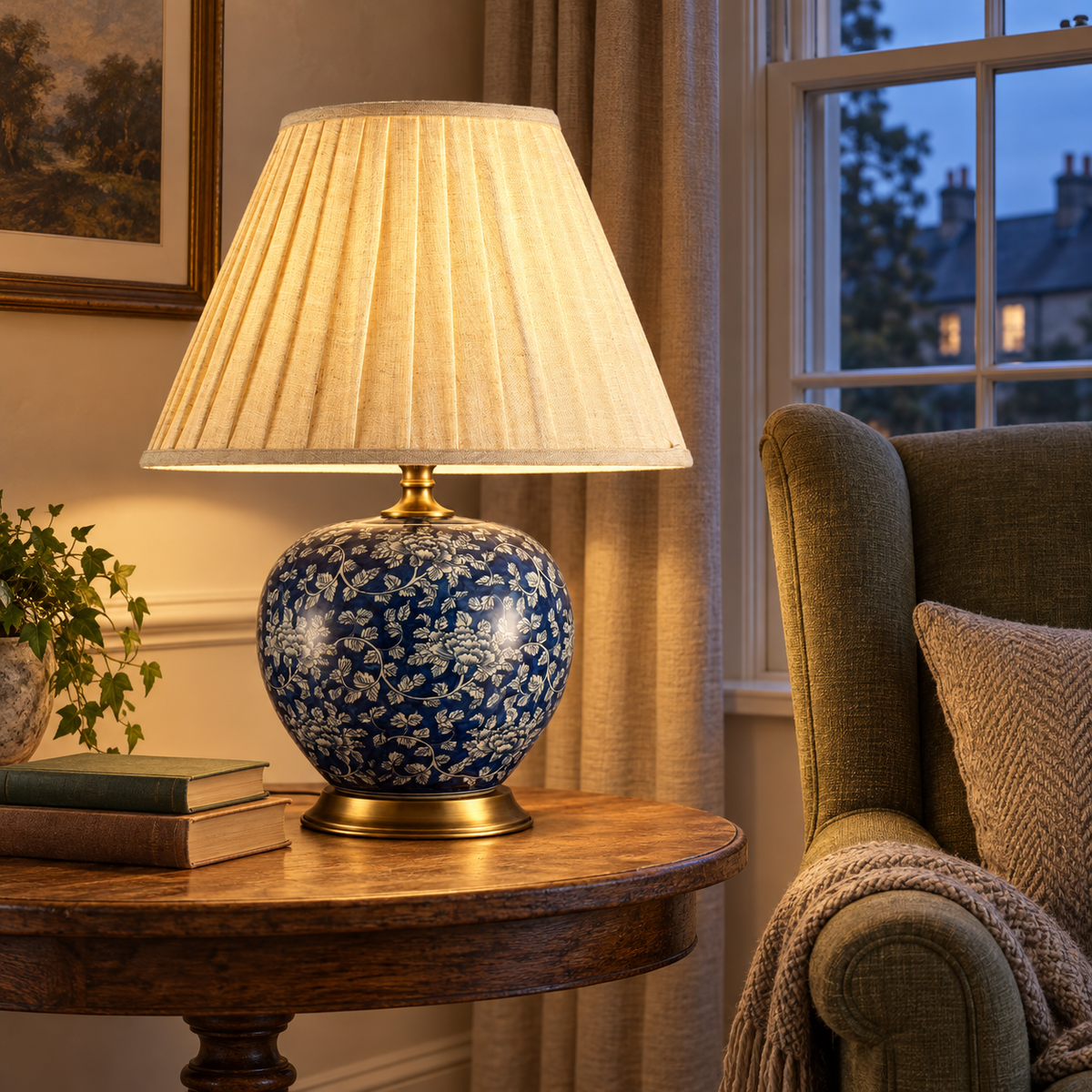 Glowing navy floral table lamp on a round side table by a living room window