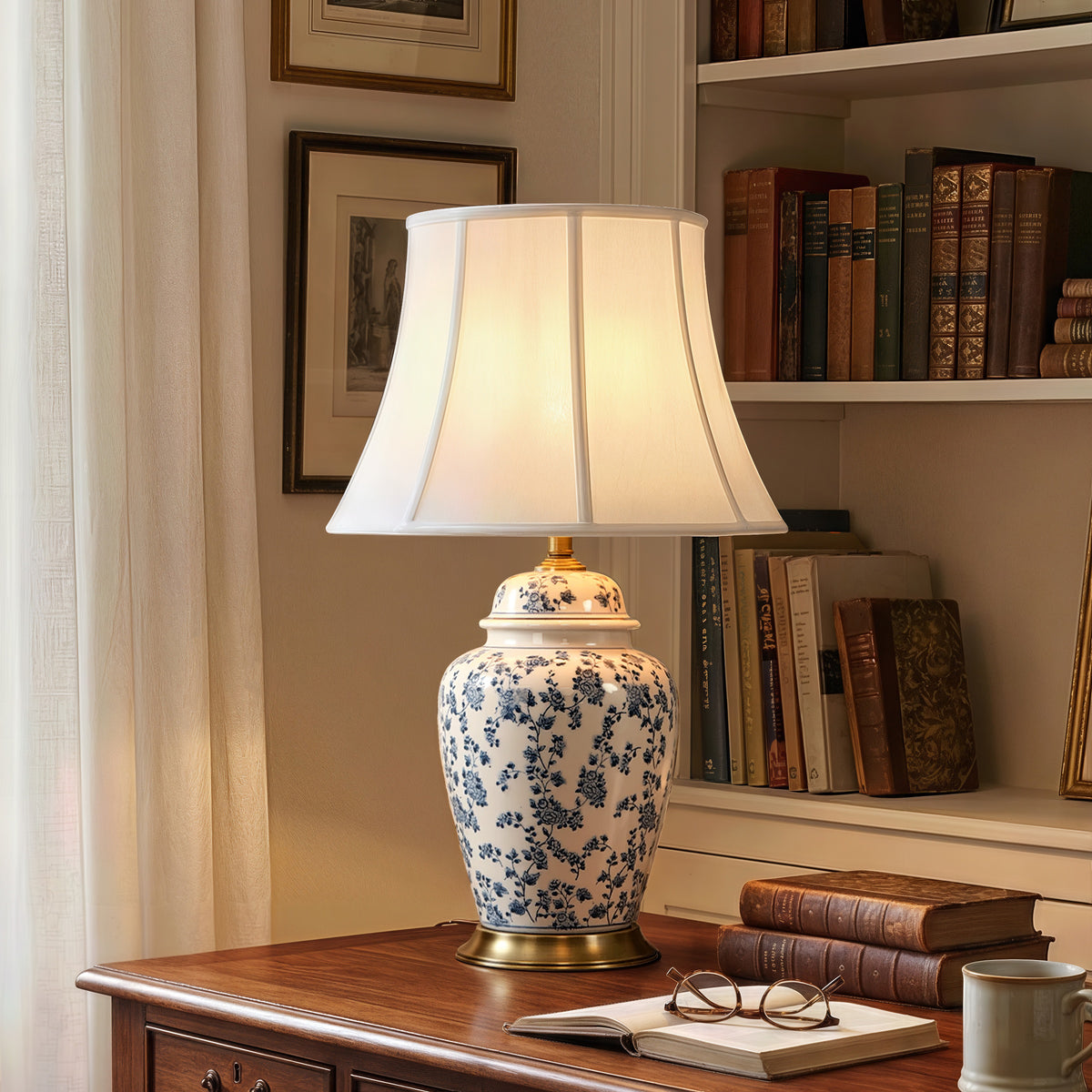 blue floral ceramic table lamp beside books by a window and bookcase